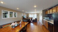 Located at 701 Fox Hill Cir in Bloomington, Illinois, this single-floor property offers a well-organized and functional layout designed for comfortable everyday living. Rich hardwood flooring flows consistently throughout the main living areas, creating a warm and cohesive aesthetic.

The open-concept living and dining area is generously proportioned, allowing the two spaces to interact naturally. The dining area features a solid wood table with seating, positioned near large windows dressed in sheer curtains that invite abundant natural light. The living room is anchored by leather seating, a central ottoman, and a flat-screen television, with colorful wall art adding visual interest against the neutral taupe walls. A large sliding glass door with vertical blinds opens to the outdoors, further brightening the space.

The kitchen runs along one wall and is equipped with warm oak cabinetry, light countertops, a double sink, and black appliances including a refrigerator, dishwasher, and microwave. A bold navy accent wall behind the counters provides a striking contrast to the cabinetry. Recessed lighting throughout ensures the space remains well-lit. A hallway with tiled flooring connects to additional rooms, completing this practical and inviting single-level layout.
