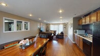Located at 701 Fox Hill Cir in Bloomington, Illinois, this single-floor property offers a well-organized and functional layout designed for comfortable everyday living. Rich hardwood flooring flows consistently throughout the main living areas, creating a warm and cohesive aesthetic.

The open-concept living and dining area is generously proportioned, allowing the two spaces to interact naturally. The dining area features a solid wood table with seating, positioned near large windows dressed in sheer curtains that invite abundant natural light. The living room is anchored by leather seating, a central ottoman, and a flat-screen television, with colorful wall art adding visual interest against the neutral taupe walls. A large sliding glass door with vertical blinds opens to the outdoors, further brightening the space.

The kitchen runs along one wall and is equipped with warm oak cabinetry, light countertops, a double sink, and black appliances including a refrigerator, dishwasher, and microwave. A bold navy accent wall behind the counters provides a striking contrast to the cabinetry. Recessed lighting throughout ensures the space remains well-lit. A hallway with tiled flooring connects to additional rooms, completing this practical and inviting single-level layout.
