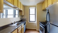 Situated in the heart of Philadelphia's prestigious Rittenhouse Square neighborhood, this single-floor space at 135 South 19th Street offers a practical and well-maintained environment. The kitchen is a standout feature, designed for efficient use of space with light wood cabinetry lining both walls from floor to ceiling, providing ample storage. Dark granite-style countertops offer a contrasting visual element, complementing the stainless steel double-basin sink and gas range. A dishwasher is seamlessly integrated beneath the countertop, adding everyday convenience. Natural light filters into the kitchen through two double-hung windows, brightening the space and offering views of the surrounding urban streetscape. The warm-toned hardwood flooring adds a natural, cohesive feel throughout. The neutral wall tones and clean lines contribute to a no-frills, functional ambiance that suits a variety of lifestyles. Positioned in one of Philadelphia's most walkable and vibrant districts, residents enjoy close proximity to Rittenhouse Square Park, upscale dining, boutique retail, and public transit options, making this a highly convenient urban address.