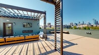 Located at 416 Vine St in Philadelphia's historic Old City neighborhood, this generously sized rooftop deck offers an exceptional outdoor living experience with panoramic views of the Philadelphia skyline. The deck is thoughtfully designed with composite wood decking in complementary tones, creating distinct zones for lounging, dining, and entertaining across its expansive footprint.

Multiple wood-framed pergolas with slatted side screens define gathering areas while allowing natural light to filter through, and string lights add ambiance for evening use. A comfortable lounge zone features low-profile sectional seating with plush cushions, complemented by bean bag chairs and a wall-mounted flat-screen TV with a built-in linear fireplace beneath it. A dedicated fire pit area is set within a gravel surround, flanked by Adirondack chairs, creating an intimate retreat. The rooftop also includes a built-in outdoor kitchen and bar area, raised planter beds with greenery, and a built-in bench with city views.

The sage-green horizontal siding of the surrounding structure ties the design together cohesively, while open sightlines ensure unobstructed views of Philadelphia's skyline in multiple directions. This rooftop is a well-appointed outdoor space ideal for both relaxation and entertainment.