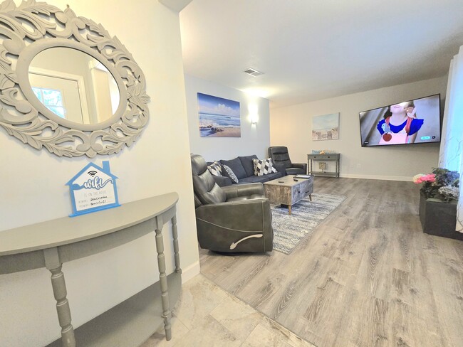 From the entryway, step into the spacious living room with 70" Roku RV, rotating recliners and sofa - 206 Cordoba St