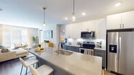 Located at 510 E Pettigrew St in Durham, NC, this single-floor residence offers a thoughtfully designed open-concept layout that seamlessly connects the kitchen, dining, and living areas. The kitchen is a standout feature, showcasing quartz countertops, a large island with an undermount sink, two-tone cabinetry with crisp white upper cabinets and slate-gray lower cabinets, a classic subway tile backsplash, and a full suite of stainless steel appliances including a French door refrigerator, electric range, built-in microwave, and dishwasher. Stylish pendant lighting above the island adds a refined finishing touch. The living area is bright and welcoming, with large windows dressed in floor-length curtains that allow abundant natural light to fill the space. Wood-look flooring runs throughout, providing warmth and continuity across the open plan. The two bedrooms are comfortably sized, each accommodating generous furniture arrangements, with large windows and ceiling fans enhancing comfort. The primary bathroom features a lengthy dual-sink vanity with quartz countertops, gray cabinetry, and matte black hardware, while the second bathroom offers a tiled tub-shower combination with a clean, modern aesthetic. Together, these spaces create a cohesive, contemporary living environment.