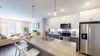 Located at 510 E Pettigrew St in Durham, NC, this single-floor residence offers a thoughtfully designed open-concept layout that seamlessly connects the kitchen, dining, and living areas. The kitchen is a standout feature, showcasing quartz countertops, a large island with an undermount sink, two-tone cabinetry with crisp white upper cabinets and slate-gray lower cabinets, a classic subway tile backsplash, and a full suite of stainless steel appliances including a French door refrigerator, electric range, built-in microwave, and dishwasher. Stylish pendant lighting above the island adds a refined finishing touch. The living area is bright and welcoming, with large windows dressed in floor-length curtains that allow abundant natural light to fill the space. Wood-look flooring runs throughout, providing warmth and continuity across the open plan. The two bedrooms are comfortably sized, each accommodating generous furniture arrangements, with large windows and ceiling fans enhancing comfort. The primary bathroom features a lengthy dual-sink vanity with quartz countertops, gray cabinetry, and matte black hardware, while the second bathroom offers a tiled tub-shower combination with a clean, modern aesthetic. Together, these spaces create a cohesive, contemporary living environment.