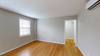 Located in Arlington, VA, this 2-bedroom, 1-bathroom residence offers a well-organized single-floor layout designed for comfortable everyday living. Warm hardwood flooring flows consistently throughout the main living areas and bedrooms, lending a cohesive and inviting feel to the space. The neutral gray and beige wall tones complement the natural wood tones, creating a clean, understated aesthetic.

The spacious primary bedroom features two windows that bring in ample natural light, while the second bedroom is also well-lit with its own window and includes a wall-mounted mini-split unit for climate control. Both rooms offer generous proportions relative to the overall footprint.

The kitchen is efficiently laid out with rich wood cabinetry, granite-style countertops, a gas range, a stainless steel sink, and tile flooring — providing all the essential amenities in a compact, functional space. A window above the counter adds natural light to the room.

The bathroom is finished in classic white subway tile with a tub-shower combination, tile flooring, and a window for ventilation and light. Hallways connect the rooms smoothly, and a dedicated entrance area provides a clear transition into the home. An electrical panel is accessible from one of the secondary areas, and the overall layout makes efficient use of the available space.