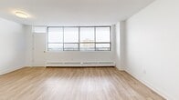 This well-appointed 2-bedroom, 1-bathroom unit at 2801 Jane Street offers a comfortable and functional layout across a single floor. Light-toned hardwood flooring runs throughout the space, lending a clean, cohesive aesthetic to every room.

The combined living and dining area is generously sized, bathed in natural light through expansive floor-to-ceiling windows that frame open city views. A private balcony extends from this area, providing an outdoor retreat. Baseboard heating lines the perimeter beneath the windows, ensuring year-round comfort.

The kitchen is thoughtfully designed with crisp white cabinetry extending to the ceiling, dark countertops, a double stainless steel sink, and a classic subway tile backsplash. Stainless steel appliances complete the space. A hallway and entrance area connect the main living spaces to the private quarters.

The spacious primary bedroom features large windows with outdoor views and baseboard heating, while the second bedroom is equally bright and well-proportioned. Both rooms benefit from easy access to the hallway. A notable feature of this unit is the exceptional storage, with six closets distributed throughout the floor plan. The full bathroom rounds out the layout, keeping the design practical and efficient. The overall ambiance is clean, modern, and light-filled.