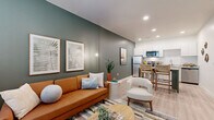 Located at 5900 N 99th Ave in Glendale, Arizona, this thoughtfully designed one-bedroom, one-bathroom unit maximizes every inch of its compact footprint. The open-concept living and kitchen area serves as the heart of the home, where a bold sage-green accent wall adds depth and character to the living space. Light wood-tone flooring runs throughout, creating a cohesive and airy feel complemented by recessed lighting overhead. A window near the entryway invites natural light into the living area, enhancing the welcoming atmosphere.

The kitchen is well-appointed with white cabinetry extending to the ceiling, stainless steel appliances including a full-size refrigerator, electric range, and built-in microwave, along with a stainless steel sink. A dining area with a pub-height table sits adjacent to the kitchen, making efficient use of the shared space.

The bedroom features plush carpeting, a wall-mounted mini-split HVAC unit for personalized climate control, and a window with blinds that allows for natural light. A dedicated closet provides practical storage.

The bathroom is finished with light tile flooring, a single-sink vanity, and a full tub-shower combination. Clean, neutral tones throughout keep the space feeling bright and functional.