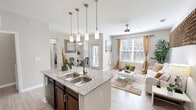 Located at 2205 W Walker St in League City, TX, this well-appointed one-bedroom, one-bathroom residence offers a thoughtfully designed single-floor layout. The open-concept living area seamlessly integrates the kitchen, dining, and living spaces, creating an airy and functional environment. The kitchen is outfitted with rich dark-stained cabinetry, granite countertops, stainless steel fixtures, a kitchen island with a double sink, pendant lighting, and black appliances including a refrigerator, range, microwave, and dishwasher. A dedicated pantry provides additional storage. The living room features light wood-look flooring, a ceiling fan, and large windows dressed with drape panels that invite abundant natural light. The dining area opens directly to a private balcony through a glass-paneled door. The bedroom is generously sized with a ceiling fan, large windows with outdoor views, and access to a spacious walk-in closet with built-in wire shelving. The bathroom includes dark cabinetry with a single vanity and a shower/tub combination. A dedicated in-unit laundry area accommodates a full-size washer and dryer. Neutral tones and wood-look flooring throughout lend the space a clean, cohesive aesthetic.