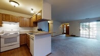 Located at 10450 W Plum Tree Cir in Hales Corners, Wisconsin, this single-floor home offers a practical and comfortable layout with a cohesive, classic design throughout. The kitchen is well-appointed with warm oak cabinetry, ample upper and lower storage, a peninsula with a countertop overhang ideal for casual seating, a double sink, and white appliances including a range, dishwasher, and refrigerator. Hardwood-style flooring grounds the kitchen area, which flows openly into the spacious living room. The living room is a highlight of the home, featuring plush carpeting, a tile-surround wood-burning fireplace, and a ceiling fan, creating a warm and inviting atmosphere. A welcoming entry foyer with a classic wood door and transom window provides natural light at the front of the home. The bedrooms are generously sized with carpeted floors, natural light from window blinds, and access to walk-in or reach-in closets with built-in shelving. The full bathroom is clean and functional, offering a tub-shower combination, a wide vanity with wood cabinetry, a large mirror, and tile flooring. Overall, the home presents a straightforward, well-maintained layout suited for comfortable everyday living.