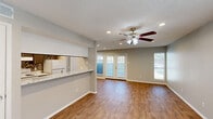 Located in Lewisville, TX, this single-floor, 2-bedroom, 1-bathroom residence offers a well-organized layout with consistent wood-look flooring throughout and a neutral gray color palette that creates a clean, cohesive aesthetic.

The open living room is bright and inviting, with recessed lighting, a ceiling fan, and French doors flanked by windows that invite natural light and provide outdoor views. The space flows naturally from the entry into the living area, creating a welcoming first impression.

The galley-style kitchen features dark cabinetry with brushed nickel hardware, marble-look countertops, a stainless steel sink, and white appliances including a refrigerator and range. Recessed lighting overhead makes the kitchen feel functional and well-lit.

Both bedrooms include ceiling fans, wood-look flooring, and soft gray walls. The primary bedroom offers generous proportions with access to a hallway leading to the bathroom, while the secondary bedroom features a window providing natural light. A closet provides additional storage.

The bathroom is neatly appointed with a tub-shower combination and wood-look flooring, maintaining the home's consistent style. A hallway connects the bedrooms and bathroom, completing the efficient single-floor floor plan. Textured ceilings are present throughout the home.