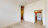 Located at 900 West Marshall Street in Richmond, Virginia, this two-bedroom, one-bathroom unit showcases an industrial loft aesthetic with soaring ceilings, exposed red ductwork, and open structural elements that lend the space a distinctive character. Light wood-look flooring runs consistently throughout, creating a cohesive and clean foundation across every room.

The main living area benefits from high ceilings with visible pipe work and a ceiling fan, giving it an open, airy feel. A compact hallway connects the living space to the rest of the unit, with a paneled entry door adding a classic touch. The kitchen is efficiently laid out in a galley configuration, featuring warm honey-toned wood cabinetry, a full-size white refrigerator, electric range, and over-the-range microwave, all complemented by recessed lighting above.

Both bedrooms are bright and simply finished. The primary bedroom is notably spacious and features exposed brick walls painted white, large windows with vertical blinds that invite generous natural light, and a sloped ceiling detail that adds architectural interest. The second bedroom similarly benefits from high ceilings with exposed industrial elements.

The bathroom is clean and functional, offering a wood-vanity with a countertop sink, a large mirror, and tile-look flooring. Overall, the unit blends industrial charm with practical, comfortable living in Richmond's vibrant Museum District neighborhood.