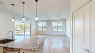 This thoughtfully designed one-bedroom, one-bathroom residence at 3550 N A W Grimes Blvd offers a comfortable and modern living experience across a single floor. The open-concept kitchen and living area forms the heart of the home, showcasing light hardwood flooring, recessed lighting, and a ceiling fan that enhances airflow and comfort. The kitchen is a standout feature, centered around a granite-topped island with an undermount sink and pendant lighting overhead. White shaker-style cabinetry provides ample storage, while stainless steel appliances — including a refrigerator, range, and microwave — complete the contemporary look. The living area is bright and airy, with multiple large windows fitted with blinds that invite natural light and offer views of the surrounding neighborhood. The bedroom is a comfortable retreat with plush carpeting, a ceiling fan, and a window that continues the theme of natural light. It provides direct access to both the full bathroom and a dedicated closet. The bathroom is elegantly finished with a granite-topped vanity, a framed mirror, and a tiled tub-shower combination, all complemented by hardwood-style flooring. Neutral tones and clean lines throughout the residence create a cohesive, modern ambiance.