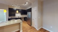 Located at 400 Blue Sky Dr in Concord, North Carolina, this single-floor residence offers a thoughtfully designed layout with a clean, contemporary aesthetic throughout. The open-concept kitchen is a standout feature, showcasing dark espresso cabinetry with sleek hardware, light granite countertops, stainless steel appliances including a refrigerator with ice dispenser, range, and built-in microwave, all complemented by warm hardwood-style flooring and track lighting overhead. A peninsula countertop provides additional workspace and a natural transition into the living area. The living space is bright and welcoming, with hardwood-style floors, a ceiling fan, and French doors with transom windows that invite natural light and provide outdoor access. The bedrooms are finished with plush carpeting, tray ceilings, ceiling fans, and multiple windows that allow for ample natural light. Closet space is provided via sliding panel doors. The bathrooms are finished consistently with dark vanity cabinetry, light countertops, brushed nickel fixtures, hardwood-style flooring, and a tub-shower combination. The overall palette of warm neutrals and contrasting dark cabinetry gives the space a cohesive and polished feel throughout.
