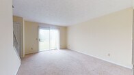 Located at 598 Colony Rd in Canal Fulton, Ohio, this multi-floor property offers a straightforward and functional layout across three levels. The main living area is generously sized, featuring plush wall-to-wall carpeting and a sliding glass door dressed with vertical blinds that opens to an outdoor view of the surrounding greenery, allowing natural light to fill the room. A staircase connects the floors, and additional carpeted rooms provide flexible space suitable for bedrooms or other uses, each with closet access and windows that bring in natural light.

The kitchen is equipped with white cabinetry, bold blue countertops, a gas range, and a full-size refrigerator. Tile flooring and a double sink complement the practical design, while a window overlooks the exterior. The full bathroom features tile flooring, a tub-shower combination with white subway tile surround, a vanity with blue countertop, and a large mirror.

The lower level presents an unfinished basement with concrete block walls, a utility sink, a sump pump, and exposed ceiling joists — offering substantial storage or the potential for future finishing. Throughout the home, neutral warm tones and consistent finishes create a cohesive, move-in ready environment.