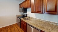 Located in Winston-Salem, NC, this single-floor residence offers a well-appointed layout designed for comfortable everyday living. The kitchen is a standout feature, showcasing rich cherry wood cabinetry, granite countertops, and a full suite of stainless steel appliances including an electric range, built-in microwave, dishwasher, and refrigerator. A breakfast bar with a granite surface connects the kitchen to the open living area, creating a seamless flow between spaces. Warm hardwood-style flooring runs throughout the kitchen and living areas, adding both durability and visual warmth to the space. The bedrooms are finished with plush neutral carpet and equipped with ceiling fans, providing a comfortable and quiet retreat. Natural light filters in through windows fitted with blinds. The bathroom continues the granite theme with a matching vanity countertop, an undermount sink, and chrome fixtures, complemented by clean tile flooring. Recessed lighting and a neutral color palette throughout the home create a bright, cohesive ambiance. This thoughtfully designed space combines practical finishes with inviting details, making it an attractive and functional home in the heart of Winston-Salem.
