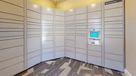 Located at Wintergreen Apartments in Loveland, Colorado, this Amazon Package Hub is a compact, single-room facility designed exclusively for secure package delivery and pickup. The entrance features a glass-paneled door clearly branded with the Wintergreen Apartments and Amazon Hub logos, providing easy identification and natural light into the space.

The interior is lined wall-to-wall with rows of Amazon Hub smart lockers finished in a neutral beige-gray tone. The lockers span floor to ceiling and wrap around two walls, maximizing storage capacity. An interactive touchscreen terminal with a keypad is integrated into the locker system, allowing residents to receive notifications and retrieve their packages with a unique pickup code.

The room features textured beige walls, white baseboards, and a patterned carpet in shades of blue and gray that adds a subtle decorative touch. The ceiling is painted a warm yellow, giving the otherwise functional space a pop of color. Recessed lighting and a security camera ensure the area remains well-lit and monitored at all times.

This purpose-built hub offers a streamlined, self-service package retrieval experience, providing residents with a secure and convenient solution for managing their deliveries around the clock.