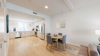 Located at 160 S Ventura Ave in Ventura, California, this contemporary two-floor residence offers a clean, modern aesthetic throughout. Light hardwood flooring flows seamlessly across the main living areas, creating a cohesive and airy feel.

The open-concept kitchen is well-appointed with light wood cabinetry extending to the ceiling, white quartz countertops, and a full suite of stainless steel appliances including a refrigerator, range, microwave, and dishwasher. Recessed lighting and a window with a roller shade provide ample illumination. The adjacent dining area comfortably accommodates a round wooden table and upholstered chairs.

The living room features a relaxed seating arrangement with warm-toned sofas and accent chairs, accented by coastal-inspired wall art that reflects the Southern California setting.

The residence includes multiple bedrooms, each finished with light walls, hardwood-style flooring, and thoughtful décor. One bedroom features bold, colorful accents, while another offers a serene, neutral palette with direct access to an en-suite bathroom complete with a frameless glass walk-in shower.

The bathrooms are finished in crisp white tile. One features a glass-enclosed shower with textured tile walls, while another offers a full tub and shower combination with a white vanity and clean chrome fixtures throughout.