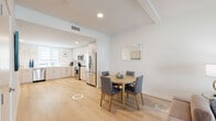 Located at 160 S Ventura Ave in Ventura, California, this contemporary two-floor residence offers a clean, modern aesthetic throughout. Light hardwood flooring flows seamlessly across the main living areas, creating a cohesive and airy feel.

The open-concept kitchen is well-appointed with light wood cabinetry extending to the ceiling, white quartz countertops, and a full suite of stainless steel appliances including a refrigerator, range, microwave, and dishwasher. Recessed lighting and a window with a roller shade provide ample illumination. The adjacent dining area comfortably accommodates a round wooden table and upholstered chairs.

The living room features a relaxed seating arrangement with warm-toned sofas and accent chairs, accented by coastal-inspired wall art that reflects the Southern California setting.

The residence includes multiple bedrooms, each finished with light walls, hardwood-style flooring, and thoughtful décor. One bedroom features bold, colorful accents, while another offers a serene, neutral palette with direct access to an en-suite bathroom complete with a frameless glass walk-in shower.

The bathrooms are finished in crisp white tile. One features a glass-enclosed shower with textured tile walls, while another offers a full tub and shower combination with a white vanity and clean chrome fixtures throughout.