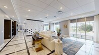 The Station at Willow Grove Clubhouse is a generously proportioned, single-floor amenity space located at 91 York Rd in Willow Grove, PA. The interior exudes a modern, upscale aesthetic anchored by striking marble-look tile flooring with dark inlay accents that flows throughout the main areas. 

The welcoming lounge greets visitors with floor-to-ceiling windows that flood the space with natural light and offer views of the surrounding area. Plush white sofas, bold blue accent chairs, and an ornate sculptural room divider with a geometric tile pattern create a refined yet inviting atmosphere. Lush greenery and curated décor add warmth throughout.

A fully appointed kitchen and bar area features a large white quartz island with gold-accented bar stools, warm walnut cabinetry, textured mosaic tile backsplash, and elegant globe pendant chandeliers, providing a stylish gathering spot for residents.

A dedicated co-working lounge offers flexible seating arrangements, pendant lighting, wall-mounted displays, and an inspiring "Teamwork" typography mural, making it ideal for collaboration or focused work.

A private media room rounds out the amenities, outfitted with plush leather reclining sofas, a large wall-mounted flat-screen TV, built-in cabinetry, acoustic wall treatments, and patterned carpet for a true cinema-like experience. Access to a fitness center is also indicated on-site.