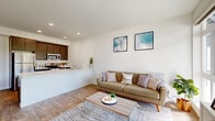 This thoughtfully designed single-floor unit presents a clean, contemporary aesthetic throughout. The open-concept layout connects the living area and kitchen seamlessly, creating a bright and functional shared space. Large floor-to-ceiling windows and a glass balcony door flood the living room with natural light while framing views of surrounding greenery. Light wood-tone flooring runs throughout, complementing the crisp white walls and modern furnishings.

The kitchen features dark espresso cabinetry with brushed silver hardware, white quartz countertops, and a full suite of stainless steel appliances, including a refrigerator, stove, microwave, and dishwasher. A peninsula counter separates the kitchen from the living space, offering both additional prep area and casual seating potential.

The living room is generously proportioned, anchored by expansive windows that extend views to the balcony beyond. Both bedrooms are well-lit and tranquil, with one offering direct balcony access. A walk-in closet provides ample storage. The bathroom is clean and functional, finished with wood-look tile flooring and a glass-enclosed shower stall. Recessed lighting throughout enhances the unit's airy, modern ambiance.