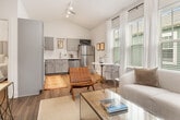 This thoughtfully designed 2-bedroom, 1-bathroom unit in Birmingham, Alabama offers an efficient and inviting layout across a single floor. The living room immediately impresses with its vaulted ceilings and ceiling fan, creating an airy sense of openness. Multiple windows dressed with sheer white curtains and blinds flood the space with natural light, while wood-look flooring runs throughout for a cohesive aesthetic.

The kitchen is well-appointed with gray shaker-style cabinetry, white quartz countertops, a white tile backsplash, and a full suite of stainless steel appliances including a refrigerator, dishwasher, range, and over-the-range microwave. A double basin sink and ample counter space add to its functionality. A compact dining area nestled beside a bright window provides a welcoming spot for meals.

The primary bedroom features vaulted ceilings, a ceiling fan, and a large window for natural light, creating a calm and restful retreat. The bathroom includes a wide vanity with a large mirror, modern light fixtures, and a glass-enclosed shower, with direct access to a walk-in closet. A dedicated laundry area houses a stacked full-size washer and dryer, adding convenience. The unit's clean, neutral palette and modern finishes create a cohesive and comfortable living environment throughout.