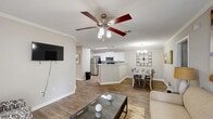 Located at 1322 N Dean Rd in Auburn, Alabama, this single-floor, 2-bedroom, 2-bathroom home offers a well-organized and comfortable layout. The living room welcomes you with hardwood-style flooring, crown molding, and natural light streaming through large windows dressed with stylish curtains, along with a front door that opens to a covered porch overlooking landscaped greenery. The kitchen is thoughtfully updated, showcasing white cabinetry, granite-look countertops, a classic subway tile backsplash, and a full suite of stainless steel appliances. Adjacent to the kitchen, the dining room features crown molding, hardwood-style flooring, and a modern chandelier overhead, creating an inviting space for meals. The spacious primary bedroom offers plush carpeting, a ceiling fan, and a window that brings in natural light. The second bedroom is equally comfortable, featuring carpet flooring, a ceiling fan, and a window with room-darkening curtains. Both bathrooms are finished with wood-look flooring and include a tub-shower combination. A dedicated laundry room with washer/dryer hookups and built-in shelving adds everyday convenience. Two closets provide ample storage throughout the home.
