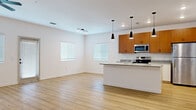 Located at 4622 Island Shores Ln in Lakeland, Florida, this single-story, one-bedroom, one-bathroom unit offers a thoughtfully designed layout with modern finishes throughout. The open-concept living and kitchen area serves as the heart of the space, featuring light hardwood-style flooring, white walls, and a ceiling fan that contribute to a bright, clean aesthetic. Multiple windows fitted with blinds allow natural light to fill the room comfortably.

The kitchen is well-equipped with warm-toned wood cabinetry, granite-style countertops, stainless steel appliances including an electric range, microwave, and refrigerator, and a peninsula with pendant lighting overhead. Recessed lighting complements the pendant fixtures for a polished look.

The bedroom is carpeted for comfort, includes a ceiling fan, and connects to a spacious walk-in closet outfitted with wire shelving for organized storage. The bathroom continues the granite countertop theme with a single vanity, large mirror, and light wood flooring.

A dedicated laundry area houses a full-size washer and dryer, adding everyday convenience. The overall design is clean, modern, and functional, making efficient use of the available space.