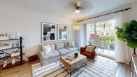 The Ascot Model in Royal Palm Beach, Florida presents a thoughtfully designed two-bedroom, one-bathroom residence that maximizes comfort and functionality across a single floor. The living room serves as the heart of the home, featuring light wood-style flooring, a ceiling fan, and floor-to-ceiling sliding glass doors that open to a private balcony overlooking lush tropical greenery and palm trees, filling the space with abundant natural light. The kitchen is outfitted with sleek light gray cabinetry, white quartz countertops, a classic subway tile backsplash, stainless steel appliances, and a convenient island for additional prep and dining space. A tucked-away in-unit stacked washer and dryer adds everyday practicality. The primary bedroom is a serene retreat, offering plush carpeting, a generous walk-in closet with built-in wire shelving, and a window framing views of surrounding greenery. The second bedroom is equally bright and restful, with soft carpet and natural light filtering through window treatments. The bathroom features a wide, illuminated vanity mirror, clean-lined cabinetry, and a sleek white countertop. Throughout the residence, a consistent palette of neutral tones and modern finishes creates a cohesive, inviting atmosphere ideal for Florida living.