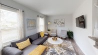 This two-floor residence offers a thoughtfully designed layout with modern finishes and a cohesive neutral color palette throughout. The kitchen is a standout feature, outfitted with stainless steel appliances including a refrigerator, electric range, microwave, and dishwasher, complemented by white shaker cabinetry, granite countertops, and a classic subway tile backsplash. Wood-look flooring runs through the main living areas, and a stacked washer and dryer unit is conveniently located just off the kitchen. The living room is bright and welcoming, featuring multiple windows that invite natural light and provide views of surrounding greenery. Neutral gray walls and wood-look flooring create a clean, versatile backdrop. The upper level hosts multiple bedrooms, each carpeted for comfort. The primary bedroom is generously sized with multiple windows, a dedicated closet, and ample room for a full furniture arrangement. The secondary bedroom also benefits from natural light through sizable windows and includes a well-organized closet. The bathroom features a granite-topped vanity with an undermount sink, polished chrome fixtures, and a well-lit mirror arrangement. Throughout the space, consistent finishes and a calm, neutral aesthetic create a cohesive and comfortable living environment across both floors.