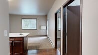 Located at 4770 Timber Pkwy S in Fargo, North Dakota, this one-bedroom, one-bathroom residence offers a functional and efficiently designed single-floor layout. The kitchen is a standout feature, showcasing rich dark-stained cabinetry, stainless steel appliances including a refrigerator, range, and microwave, and an extended white countertop peninsula that transitions seamlessly into the living area. Hard surface flooring runs through the kitchen, while plush carpeting covers the living and bedroom areas, adding warmth throughout. Natural light filters into the living space through large windows dressed with horizontal blinds, complemented by baseboard heating for year-round comfort. The bedroom is a comfortable, well-proportioned retreat featuring its own window and direct access to a generously sized walk-in closet outfitted with wire shelving and hanging rods. The full bathroom includes a soaking tub and shower combination with clean white surround panels and tile-style flooring. A dedicated in-unit laundry area with full-size washer and dryer hookups and additional wire shelving provides practical convenience. Neutral wall tones and dark wood trim accents create a cohesive, move-in-ready aesthetic throughout the space.