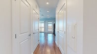 Located at 480 Morrissey Blvd in Boston's Dorchester neighborhood, this modern single-floor studio offers a thoughtfully designed open layout that maximizes every square foot. The space is anchored by warm hardwood flooring that runs throughout, complemented by crisp white walls and recessed lighting that create a bright, clean aesthetic.

The combined kitchen and living area serves as the heart of the unit. The kitchen is well-appointed with gray shaker-style cabinetry, a striking blue vertical tile backsplash, stainless steel appliances — including a refrigerator, gas range, dishwasher, and built-in microwave — and a deep sink. Large windows flood the kitchen and living area with generous natural light and frame open city views, while a glass-panel balcony door in the living space provides direct outdoor access and additional sunlight.

A dedicated hallway connects the main living area to the bathroom and utility spaces. The bathroom features light wood-toned flooring consistent with the rest of the unit, a gray vanity with a sink, and a clean, minimalist finish. Additional built-in storage panels are incorporated into the hallway design for practical use.

The overall ambiance is contemporary and light-filled, with a cohesive neutral palette and modern finishes throughout, making this an efficient and stylish urban residence.