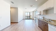 This 2-bedroom, 2-bathroom unit offers a well-organized, single-floor layout designed for functional living. The open-concept kitchen and living area serves as the heart of the space, featuring light wood-tone flooring, recessed lighting, and large windows that frame expansive panoramic views of the surrounding cityscape and distant mountains. The kitchen is equipped with two-tone cabinetry—white upper cabinets paired with warm wood-grain lower cabinets—granite countertops, and a full suite of white appliances including a range, microwave, dishwasher, and refrigerator.

The primary bedroom is generously proportioned and benefits from floor-to-ceiling windows on two walls, flooding the room with natural light and offering sweeping elevated views. The second bedroom features plush carpeting, a sliding closet, and access to the hallway. Both bedrooms are finished in neutral tones that complement the overall aesthetic.

The two bathrooms are cleanly designed; one features a soaking tub with shower combination, while the other includes a standalone walk-in shower with built-in shelving. Both bathrooms include wood-toned vanities with granite countertops and wood-look flooring, maintaining a cohesive, contemporary style throughout the unit.