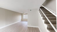 This two-story home offers a well-organized layout spread across two floors, providing comfortable living spaces for everyday use. The main level houses the combined living and dining area, which features light luxury vinyl plank flooring, neutral warm-beige walls, a ceiling fan, and a carpeted staircase leading to the upper floor. Natural light flows in through blinds-fitted windows, lending an airy, open feel to the common areas. The kitchen is thoughtfully equipped with white shaker-style cabinetry, light marble-look countertops, a white subway tile backsplash, and black appliances including an electric range, dishwasher, and refrigerator, complemented by a stainless steel sink and recessed lighting. The upper floor hosts all three bedrooms, connected by a hallway and served by five closets for generous storage. The bedrooms feature plush carpet flooring, neutral walls, and windows that bring in natural light. The primary bedroom offers a notably spacious footprint. The single full bathroom includes a tiled tub-shower surround, clean white finishes, and a window for natural ventilation. Throughout the home, crisp white trim and a consistent neutral color palette create a cohesive, clean aesthetic.