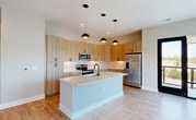 Located at 4362 Watermark Dr in Wilmington, NC, this modern apartment offers 1,290 square feet of thoughtfully designed single-floor living across 3 bedrooms and 2 bathrooms. The open-concept kitchen and living area serves as the heart of the home, showcasing light wood cabinetry, stainless steel appliances, a white quartz waterfall island with an undermount sink, and stylish pendant lighting. Light-toned hardwood-style flooring flows throughout the main living areas, complemented by large floor-to-ceiling sliding glass doors that flood the space with natural light and provide direct access to a private balcony with open outdoor views. The bedrooms feature plush carpeting, ceiling fans, and windows offering natural light and scenic views of the surrounding landscape. The primary bedroom measures 150 square feet and includes a dedicated closet with built-in shelving and hanging rods. The bathrooms are finished with light wood vanities, white quartz countertops, and matte black fixtures, with one bathroom featuring a full soaking tub and shower combo. Two closets and two hallways provide ample storage and connectivity throughout the unit. Part of a contemporary multi-story residential community, this apartment combines clean architectural lines with functional, modern living.