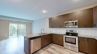 Located at 15315 Maple Island Rd in Burnsville, Minnesota, this well-appointed one-bedroom, one-bathroom residence offers a thoughtfully designed single-floor layout with a clean, neutral aesthetic throughout. Light-toned, wood-style flooring runs through the main living areas, complementing the warm beige wall palette that creates a cohesive and inviting atmosphere.

The combined kitchen and living area serves as the heart of the home. The kitchen stands out with rich, walnut-toned cabinetry, granite countertops, a classic white subway tile backsplash, and a full suite of stainless steel appliances including a range, over-the-range microwave, and a side-by-side refrigerator. A peninsula with an undermount sink adds additional counter space and casual dining potential. The living area benefits from a sliding glass door that opens to the outdoors, filling the space with natural light and greenery views.

The bedroom is a comfortable retreat, carpeted for warmth, and features a ceiling fan, a multi-pane window with outdoor views, and direct access to a walk-in closet outfitted with wire shelving for organized storage. The bathroom includes a walk-in shower with a grab bar and clean, minimalist finishes. The overall design prioritizes functionality and comfort in an efficient, well-utilized footprint.