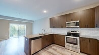 Located at 15315 Maple Island Rd in Burnsville, Minnesota, this well-appointed one-bedroom, one-bathroom residence offers a thoughtfully designed single-floor layout with a clean, neutral aesthetic throughout. Light-toned, wood-style flooring runs through the main living areas, complementing the warm beige wall palette that creates a cohesive and inviting atmosphere.

The combined kitchen and living area serves as the heart of the home. The kitchen stands out with rich, walnut-toned cabinetry, granite countertops, a classic white subway tile backsplash, and a full suite of stainless steel appliances including a range, over-the-range microwave, and a side-by-side refrigerator. A peninsula with an undermount sink adds additional counter space and casual dining potential. The living area benefits from a sliding glass door that opens to the outdoors, filling the space with natural light and greenery views.

The bedroom is a comfortable retreat, carpeted for warmth, and features a ceiling fan, a multi-pane window with outdoor views, and direct access to a walk-in closet outfitted with wire shelving for organized storage. The bathroom includes a walk-in shower with a grab bar and clean, minimalist finishes. The overall design prioritizes functionality and comfort in an efficient, well-utilized footprint.