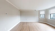 Located at 12–32 Garrison St in Boston's South End (02116), this 740-square-foot, single-floor apartment offers a thoughtfully designed 2-bedroom layout with a living room, kitchen, and hallway. Light wood flooring runs throughout the entire unit, lending a warm, cohesive aesthetic to every room. The kitchen features stainless steel appliances—including a range, over-the-range microwave, and dishwasher—set against granite countertops and dark-toned cabinetry, offering a sleek and functional cooking space. The living room is generously proportioned with crown molding and multiple windows fitted with roller shades, filling the space with natural light and city views. Both bedrooms continue the light hardwood flooring, neutral wall tones, and large windows with roller shades. The primary bedroom measures 130 square feet and includes a built-in closet system with shelving and dual hanging rods for efficient storage. The second bedroom also benefits from ample natural light via its own window. Throughout the unit, clean white baseboards, panel-style doors with brushed nickel hardware, and a neutral color palette contribute to a modern, move-in-ready atmosphere.