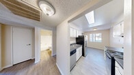 Located at 5160 Tamarus St in Las Vegas, NV, this single-story 3-bedroom, 2-bathroom unit offers a practical and well-organized layout across a comfortable footprint. The living room features light wood-style flooring and a sliding glass door that opens to an outdoor area, allowing natural light to fill the space with views of the surrounding exterior.

The galley-style kitchen is efficiently designed with white cabinetry lining both sides, dark granite-style countertops, and stainless steel appliances including a refrigerator and electric range. A skylight above the kitchen transition area brings in additional natural light, enhancing the bright, airy feel of the space. Light wood-style flooring continues throughout the main living and kitchen areas.

The three bedrooms are carpeted and finished with neutral tones, offering a clean and comfortable feel. The primary bedroom provides a generous amount of space. Two hallways and two closets support organized storage throughout the unit.

Both bathrooms are finished with wood-style flooring, granite-style vanity countertops, and clean white fixtures. One bathroom features a full tub-shower combination. Textured ceilings are consistent throughout the home, complementing the warm, neutral color palette that unifies each room.
