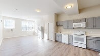 Located at 366 W Allen St in Allentown, PA, this efficiently designed single-floor unit offers a thoughtfully arranged layout that maximizes its available footprint. The open-concept kitchen and living area serves as the heart of the space, bathed in natural light streaming through multiple windows fitted with blinds. Light-toned luxury vinyl plank flooring runs throughout, lending a clean, cohesive look to the interior.

The kitchen is well-equipped with grey shaker-style cabinetry featuring brushed nickel hardware, white appliances including an electric range, dishwasher, microwave, and refrigerator, complemented by light countertops and a stainless steel sink. Flush-mount ceiling fixtures provide consistent overhead lighting throughout the unit.

The living area is generously proportioned relative to the overall footprint, with large windows on multiple walls that flood the room with natural light and offer views of the surrounding neighborhood. A wall-mounted window AC unit provides climate control.

Two hallways connect the main living spaces to the bathroom, which features a full tub/shower combination with a white surround, toilet, and towel bar. Neutral warm-beige walls throughout create a bright, inviting atmosphere well-suited for comfortable everyday living.