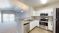 Located at 7550 S Blackhawk St in Englewood, CO, this well-appointed single-floor, 3-bedroom, 2-bathroom home offers a thoughtfully designed layout with comfortable living spaces throughout. The open-concept living room is a standout feature, boasting vaulted ceilings that lend an airy, expansive feel, soft carpeting underfoot, and a classic white-mantled fireplace as a focal point. Sliding glass doors flood the space with natural light and provide outdoor access. A pendant light marks the transition into the kitchen, which features white raised-panel cabinetry, granite-style countertops, a peninsula breakfast bar, wood-look flooring, and a full suite of stainless steel appliances including a refrigerator, range, microwave, and dishwasher. The spacious primary bedroom includes a walk-in closet, offering ample storage. Two additional bedrooms are carpeted and bright, each with natural light from well-placed windows. The bathrooms are finished with white vanities, wood-look flooring, and tub-shower combinations accented by a distinctive teal tile border. Three closets are distributed throughout the home, ensuring generous storage. The overall aesthetic is clean, neutral, and move-in ready.