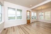 This well-appointed two-story home showcases a thoughtful blend of modern design and functional living. The entry greets visitors with a warm, wood-framed glass door flanked by large windows that flood the space with natural light and offer views of the surrounding neighborhood. Light hardwood flooring flows throughout the main level, complementing the home's clean, neutral palette.

The gourmet kitchen is a standout feature, boasting white shaker cabinetry paired with dark upper cabinets, grey quartz countertops, a grey tile backsplash, and stainless steel appliances including a French door refrigerator. A central island with a wood-toned base provides additional prep space, while globe and chandelier pendant lights add a contemporary touch. The adjacent dining area is bright and airy, highlighted by an elegant black-and-gold ring chandelier.

The upper level features carpeted bedrooms with generous closet space, including sliding panel closets. The bathrooms are finished to a high standard, with large-format marble-look tile, a sliding glass-enclosed walk-in shower with matte black hardware, a soaking tub, warm wood vanities, and grey countertops. Each room receives ample natural light through well-placed windows, lending the entire home an open, inviting ambiance.