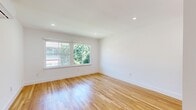 Located on Princeton Street in Santa Monica's desirable 90403 zip code, this two-bedroom, one-bathroom unit offers a thoughtfully designed single-level layout. Warm honey-toned hardwood floors run throughout the living areas and bedrooms, reflecting natural light and lending a clean, cohesive aesthetic across the space.

The living room provides an open, airy feel with recessed lighting and crisp white walls. The renovated kitchen is well-appointed with white shaker cabinets, quartz countertops, black hardware accents, stainless steel appliances including a gas range and dishwasher, and distinctive dark hexagonal tile flooring, creating a functional and stylish cooking space with a window bringing in natural light.

Both bedrooms feature large windows framing views of mature greenery, recessed lighting, and wall-mounted mini-split HVAC units for individual climate control. The primary bedroom includes a closet with louvered doors. The bathroom has been fully updated with a white vanity topped with stone counters, a tub-shower combination, black fixtures, and herringbone tile flooring, maintaining the home's clean, modern character throughout.