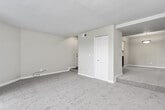 This single-story residence features three bedrooms, two bathrooms, a living room, kitchen, utility room, and multiple hallways connecting the thoughtfully arranged floor plan. The spacious living room is highlighted by plush carpeting, a ceiling fan with light fixture, textured ceiling, and a sliding glass door fitted with vertical blinds that opens to an outdoor balcony, allowing ample natural light and exterior views.

The galley-style kitchen features wood-look flooring, white cabinetry with light stone-pattern countertops, black appliances including an electric range and refrigerator, a stainless steel sink, and track lighting overhead. The primary bedroom is generously sized, featuring carpet, a ceiling fan, and a window with outdoor views. Additional bedrooms are similarly carpeted with ceiling fans. Two closets provide dedicated storage, including one with built-in double shelving rods.

Both bathrooms include white vanity cabinetry, light stone-pattern countertops, and tub-shower combinations. One bathroom features wood-look flooring and a framed mirror, while the other offers a sleek brushed-nickel fixture set and pendant lighting. Textured walls and ceilings are consistent throughout, contributing to a cohesive, neutral aesthetic across the entire residence.