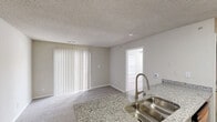 Located at 3200 Todds Rd in Lexington, Kentucky, this well-appointed one-bedroom, one-bathroom unit offers a thoughtfully designed single-floor layout that makes excellent use of its compact footprint. The open-concept kitchen serves as a central hub, showcasing granite countertops, a double-basin sink set into a peninsula, gray shaker-style cabinetry, and a full suite of stainless steel appliances including a refrigerator, range, and microwave. Wood-look flooring runs through the kitchen and entry areas, lending warmth and easy maintenance. The living room flows naturally from the kitchen and features plush carpeting, a textured ceiling, and vertical blinds covering a large sliding door that brings in generous natural light. The bedroom is a bright, carpeted retreat with two windows fitted with horizontal blinds, a ceiling fan with integrated light, and a double-door closet providing ample storage. A dedicated pantry and additional closet further enhance storage throughout the unit. The bathroom is finished with gray vanity cabinetry, a lighted mirror, and wood-look flooring, maintaining a consistent, clean aesthetic. A utility room rounds out the floor plan, adding practical functionality to this efficiently designed space.