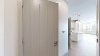 This well-appointed two-bedroom, two-bathroom residence offers a thoughtfully designed single-floor layout with contemporary finishes and a clean, modern aesthetic. The open-concept kitchen and living area serves as the heart of the home, where wood-look flooring flows throughout. The kitchen is outfitted with white shaker cabinetry accented by gold hardware, stainless steel appliances including a refrigerator, range, microwave, and dishwasher, and a central island beneath a trio of globe pendant lights — an elegant focal point for the space. The adjacent living and dining area is generously sized, bathed in natural light from a wide bank of windows, and finished with a gold chandelier that adds a refined touch.

Both bedrooms feature plush carpet flooring and ceiling fans. The primary bedroom is a comfortable retreat of notable size, while the second bedroom also benefits from natural light via a dedicated window. A spacious walk-in closet with wire shelving and hanging rods provides ample storage.

The bathrooms are finished with marble-look tile flooring, white vanities with gold hardware, and a full tub-shower combination. A dedicated laundry room houses a full-size washer and dryer alongside a water heater and overhead shelving, adding practical convenience to this well-rounded residence.