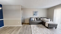 Located in Ridgeland, MS, this 2-bedroom, 2-bathroom single-floor residence offers a thoughtfully laid-out floor plan designed for comfortable, everyday living. The living room serves as the heart of the home, featuring wood-look plank flooring, neutral warm-toned walls, and a textured ceiling. A sliding glass door with vertical blinds fills the space with natural light and provides access to an outdoor patio, while a wall-mounted TV adds a modern touch. The galley-style kitchen is efficiently designed with white cabinetry, light quartz countertops, wood-look flooring, and stainless steel appliances, including a refrigerator, dishwasher, and electric range. The primary bedroom is generously sized with plush carpet flooring, a ceiling fan, and a closet with mirrored sliding doors and built-in shelving. The second bedroom also features carpet, a ceiling fan, a natural window, and its own closet. Both bathrooms are clean and functional — one features a white vanity with a quartz countertop and framed mirror, while the other includes a tub-shower combination. A hallway connects the rooms, completing this well-organized and move-in-ready home.