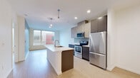 Located in Seattle's vibrant University District, this modern 1-bedroom, 1-bathroom unit on Roosevelt Way NE offers a well-designed open-concept layout with contemporary finishes throughout. Light wood-tone flooring flows seamlessly across the entire space, complementing the clean, minimalist aesthetic.

The combined living, dining, and kitchen area forms the heart of the unit. The kitchen is outfitted with stainless steel appliances — including a full-size refrigerator, electric range, and built-in microwave — alongside two-tone cabinetry featuring light wood upper cabinets and dark lower cabinets. A central island with a white countertop and integrated sink provides additional prep space and casual dining. Pendant lighting adds a stylish focal point overhead, while recessed lighting ensures the area is well illuminated. Large windows draw in natural light and offer views of the surrounding neighborhood.

The bedroom is a comfortable, serene retreat with neutral walls and large windows that provide ample daylight. Two closets offer generous storage throughout the unit. The bathroom features a full tub-shower combination, and the unit conveniently includes in-unit laundry. This thoughtfully laid-out residence delivers a clean, modern living experience in one of Seattle's most accessible and dynamic neighborhoods.