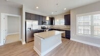 Located at 2425 Croquet Dr in Wilmington, NC, this single-floor residence offers a thoughtfully designed layout with contemporary finishes throughout. The kitchen is a standout feature, showcasing dark slate-toned shaker cabinets, granite countertops, a central island with additional counter space, stainless steel appliances including a range, microwave, dishwasher, and refrigerator, all set atop light wood-look flooring that flows seamlessly through the main living areas. The open living area is bright and airy, with sliding glass doors that lead to a covered balcony featuring a natural wood deck, white railings, and open views of the surrounding community. The bedrooms are finished with plush carpet and receive ample natural light through large windows with blinds. The primary bathroom includes dark cabinetry with granite countertops, wood-look flooring, and direct access to a spacious walk-in closet outfitted with wire shelving and carpet. A second full bathroom mirrors the same refined aesthetic and includes a tub-shower combination. Neutral gray tones on the walls create a clean, cohesive look throughout, giving the space a modern and welcoming ambiance.