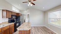 Located at 3127 Maverick Loop in Oyster Creek, TX, this thoughtfully designed single-story, one-bedroom, one-bathroom home makes excellent use of its compact footprint. The open-plan kitchen and dining area serves as the heart of the home, anchored by a striking granite-topped center island with a warm wood base and bar seating. Rich, dark wood cabinetry lines the walls, complemented by black appliances, a stainless steel refrigerator, and granite countertops. Vaulted ceilings with clerestory windows flood the kitchen with natural light, while a ceiling fan adds comfort and airflow. Light-toned luxury vinyl plank flooring runs throughout, creating a cohesive and easy-to-maintain surface. The living and dining areas are bright and open, benefiting from multiple windows and a glass exterior door that invites additional natural light. A wall-mounted mini-split system ensures efficient climate control. The bedroom is a comfortable retreat featuring vaulted ceilings, a ceiling fan, two louvered closets, warm wood cabinetry with granite accents, and transom windows that allow soft natural light without sacrificing privacy. The bathroom is conveniently accessible from the main living area. Clean lines, neutral tones, and quality materials throughout give this home a polished, move-in-ready feel.
