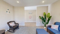 Located at 2309 Mooring Ln in Boiling Springs, SC, this single-story community amenity center offers a well-appointed collection of shared spaces designed to support an active and convenient lifestyle. The interior is finished throughout with warm, neutral-toned walls, crisp white trim, and light hardwood-style flooring that lends a clean, cohesive aesthetic across all areas.

The lounge area serves as a welcoming gathering space, featuring large windows flanked by a glass-paneled entry door that floods the room with natural light and provides views of the surrounding community. Comfortable wicker furnishings with blue cushions and decorative accents create an inviting atmosphere ideal for relaxation or socializing.

The fitness center is generously sized and well-equipped, housing multiple treadmills, stationary bikes, an elliptical, and a rowing machine. Recessed lighting and multiple windows ensure the space remains bright, while the open layout allows for comfortable movement between equipment.

A dedicated laundry room provides practical convenience, outfitted with multiple top-loading washing machines and dryers arranged in a row. Tile flooring and a bright window complete this functional space. Two bathrooms serve the facility, and the overall layout — as illustrated by the dollhouse view — flows intuitively from one area to the next, making the amenity center easy to navigate and use.