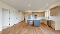 Located in Minnetonka, MN, this single-floor, 3-bedroom, 2-bathroom home offers a well-designed layout with modern finishes throughout. The open-concept kitchen and living area serves as the heart of the home, featuring light wood cabinetry, stainless steel appliances, a white subway tile backsplash, and a central island with a contrasting blue-gray base and white countertop — ideal for both cooking and entertaining. Light wood-plank flooring runs throughout the main living areas, enhancing the bright, airy feel.

The generously sized primary bedroom features large black-framed windows overlooking a lush outdoor landscape, filling the space with natural light, and is complemented by a dedicated walk-in closet with built-in wire shelving. The two additional bedrooms are carpeted and also benefit from windows with outdoor views. The home includes five closets in total, providing ample storage throughout.

Both bathrooms are finished with light wood vanities, black hardware accents, and wood-look flooring. The primary bathroom features a sleek walk-in shower with white subway tile and a sliding glass door with a matte black frame. A hallway with recessed lighting connects the bedrooms, and the home also includes a laundry room and utility room for added convenience.